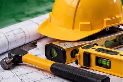 Hard hat, spirit levels and hammer on construction blueprints